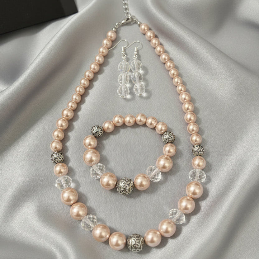 Pearl necklace, bracelet, and earrings set on a black surface