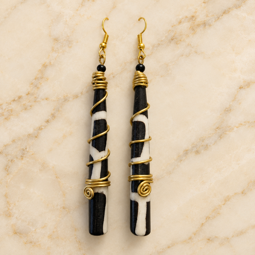 Long cylindrical drop earrings with gold-tone details on a cream marble background