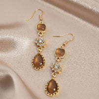 Pair of gold and brown earrings on a white background