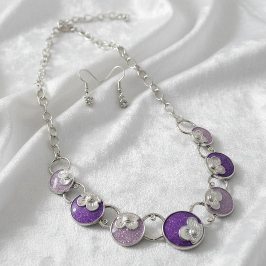 Necklace and earrings set with purple and silver circular pendants on a dark background