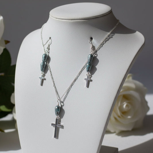 Necklace and earrings with cross pendants on a light gray surface