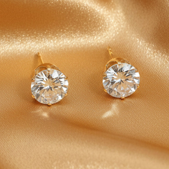 Gold stud earrings with clear gemstones on a white background