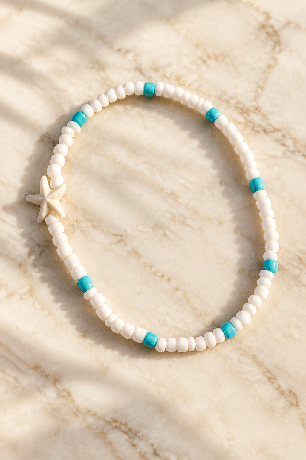White Coastal Starfish Stretch Anklet on cream marble